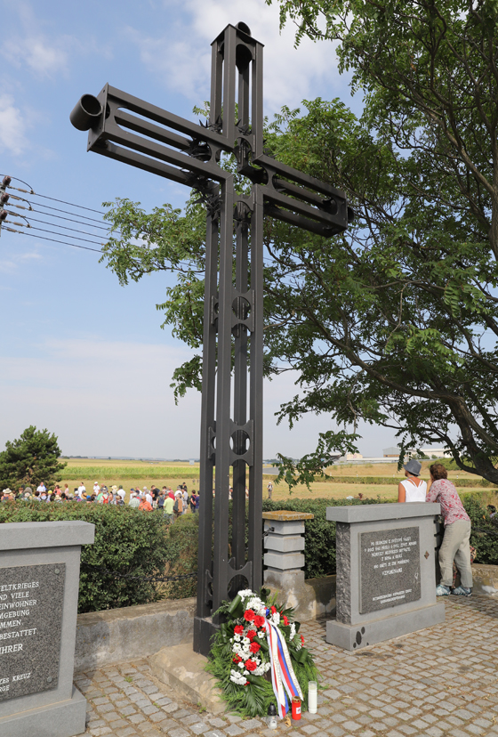 U památníku je vztyčený velký kovový kříž. 