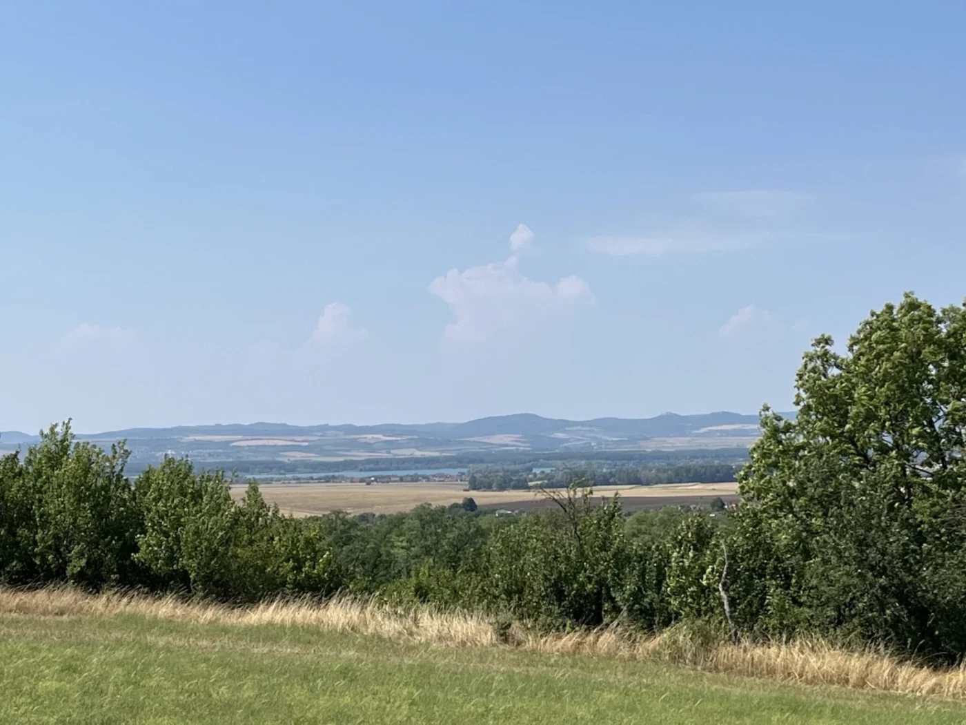 Přes pole jsou vidět štěrkopísková jezera v Ostrožské Nové Vsi a v dáli Buchlov a Barborka. 