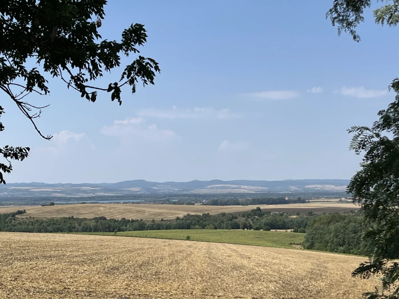 Přes pole jsou vidět štěrkopísková jezera v Ostrožské Nové Vsi a v dáli Buchlov a Barborka. 